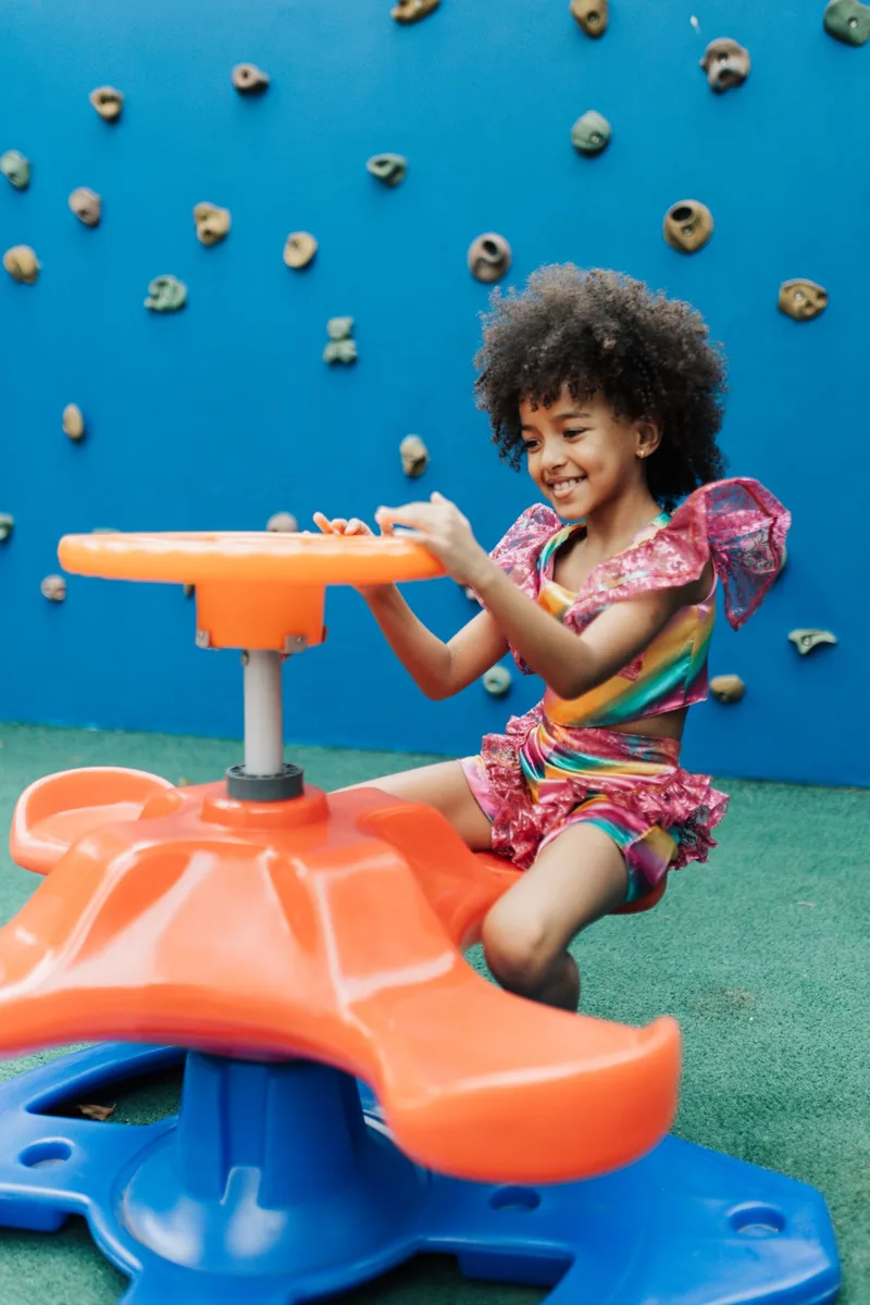 Happy child in colorful outfit enjoying playtime on vibrant playground with climbing wall