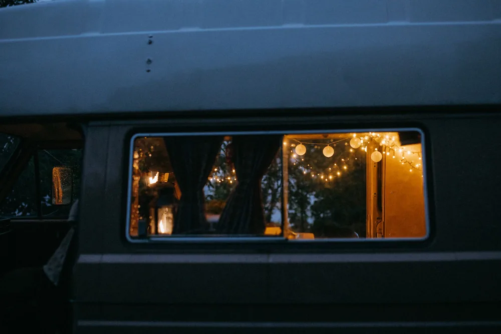 Warm ambiance inside a camper van with string lights glowing at dusk