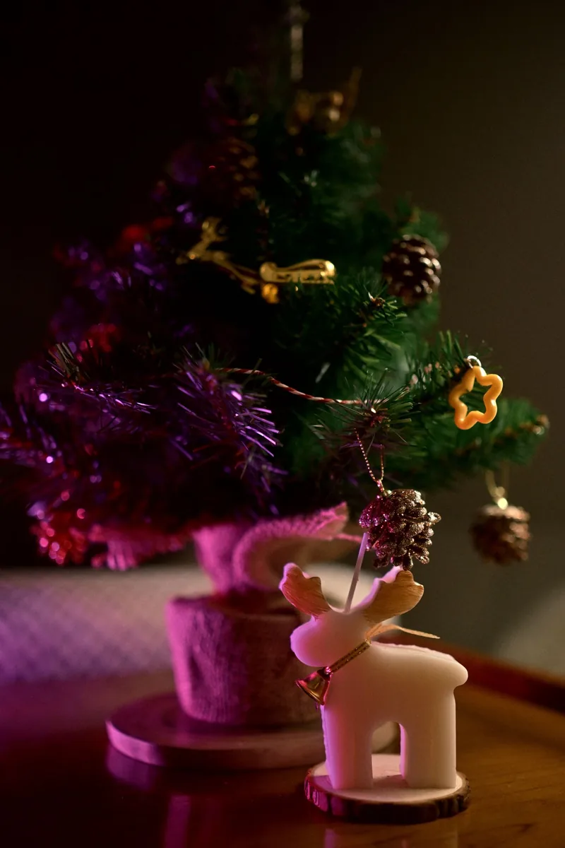 Small Christmas tree with ornaments and reindeer decoration on a wooden table